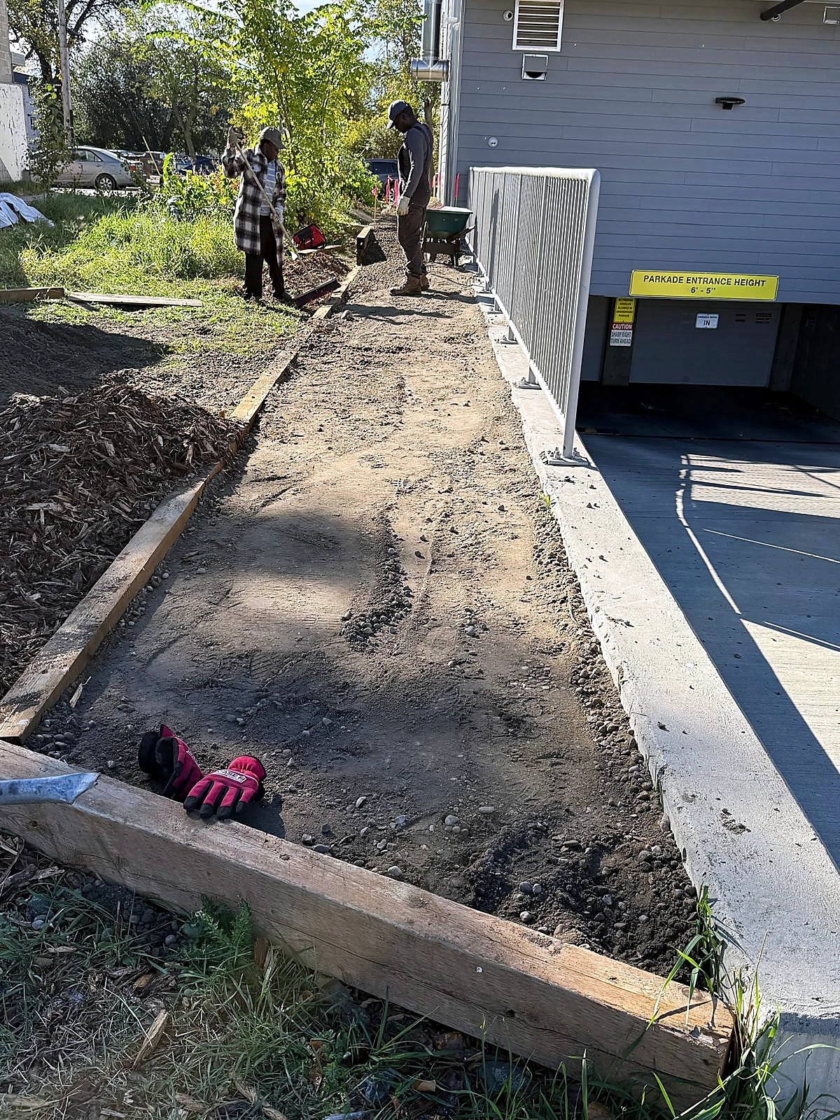 Team leveling grade beside a building and parkade entrance for landscaping finish work